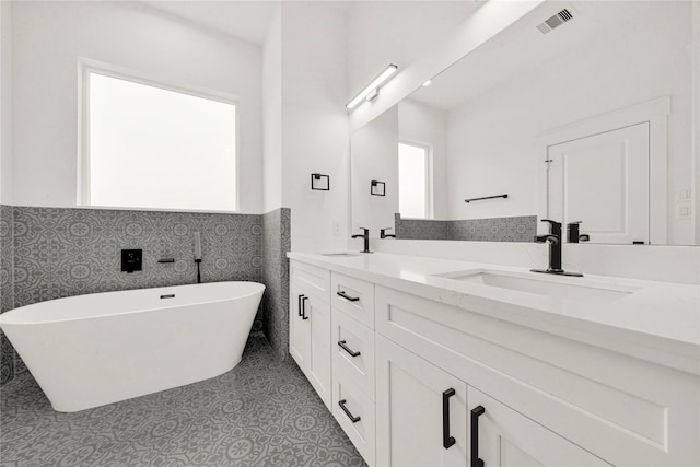 full bath featuring a sink, visible vents, a soaking tub, and double vanity