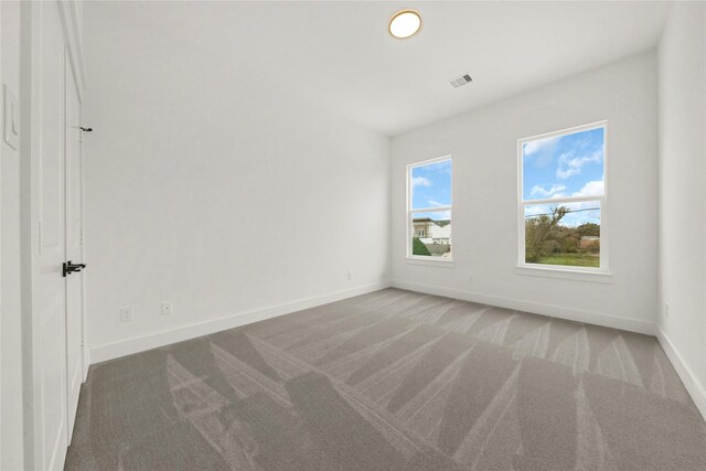 unfurnished room with baseboards, visible vents, and light carpet