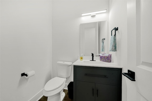 bathroom featuring toilet, vanity, baseboards, and wood finished floors