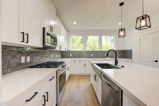 kitchen with a sink, light stone counters, decorative light fixtures, tasteful backsplash, and stainless steel appliances