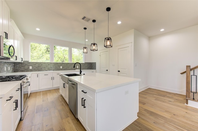 kitchen featuring backsplash, visible vents, light wood finished floors, and stainless steel appliances