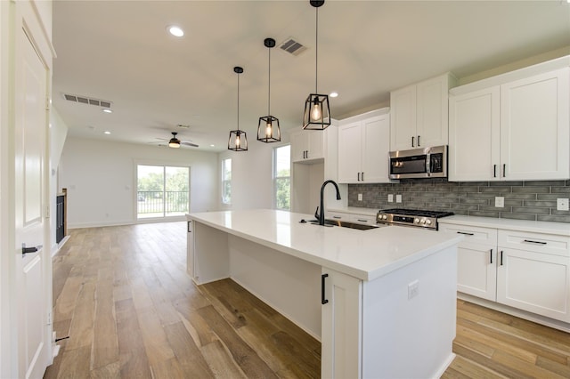 kitchen with a sink, visible vents, backsplash, and stainless steel appliances