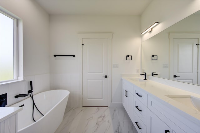 full bath with double vanity, a soaking tub, marble finish floor, and a sink