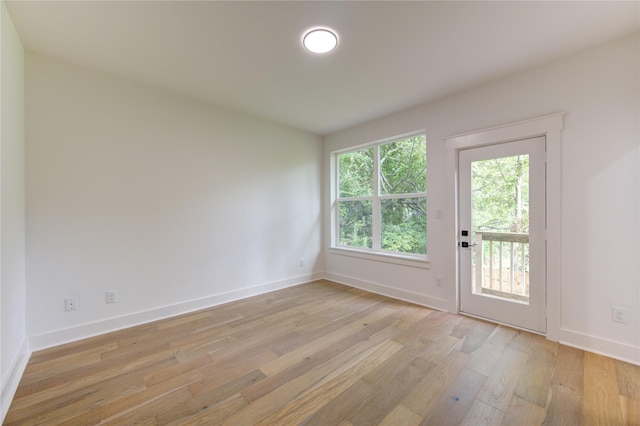 spare room featuring baseboards and light wood-type flooring