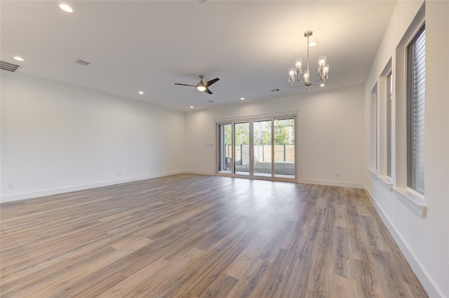 spare room featuring light wood-style flooring, ceiling fan with notable chandelier, baseboards, and recessed lighting