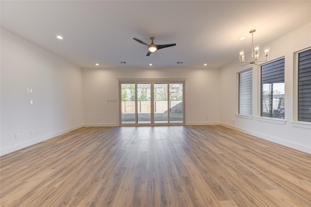 unfurnished room with light wood-style floors, ceiling fan with notable chandelier, baseboards, and recessed lighting