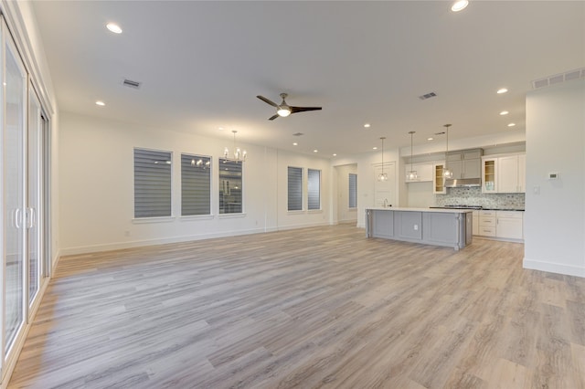 interior space with a center island, visible vents, hanging light fixtures, open floor plan, and white cabinets