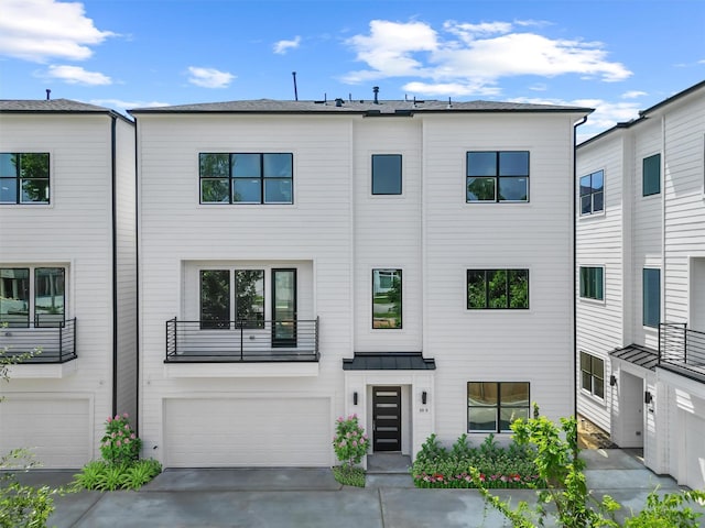 townhome / multi-family property with a standing seam roof, driveway, an attached garage, and metal roof