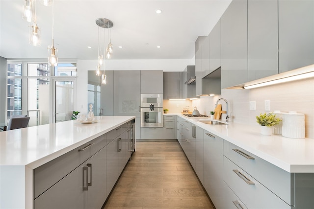 kitchen with decorative light fixtures, a large island, light countertops, gray cabinetry, and modern cabinets