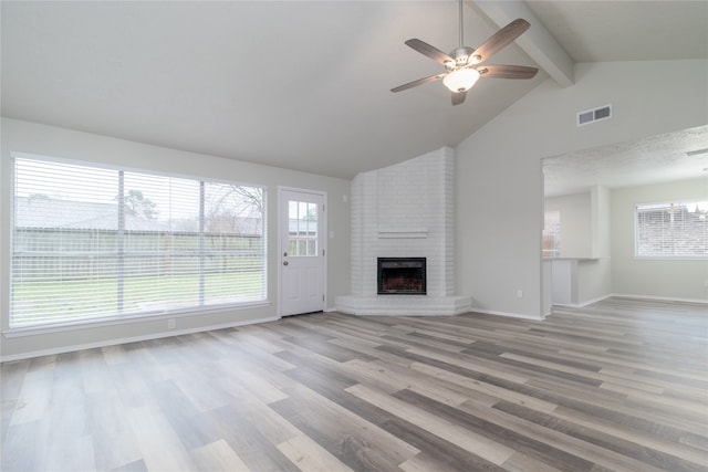 unfurnished living room featuring beam ceiling, a fireplace, light wood finished floors, visible vents, and baseboards