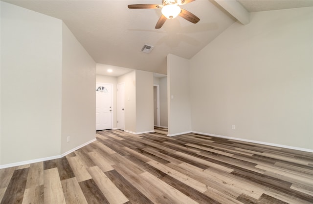 unfurnished room featuring baseboards, visible vents, a ceiling fan, wood finished floors, and vaulted ceiling with beams