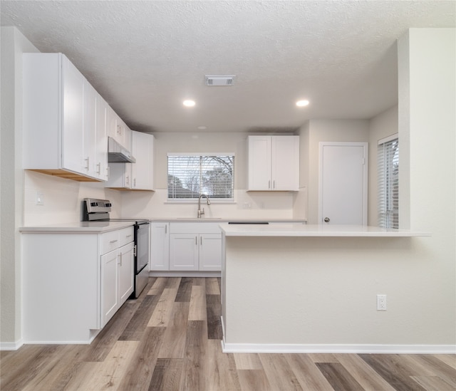 kitchen with under cabinet range hood, visible vents, white cabinetry, stainless steel range with electric cooktop, and light countertops