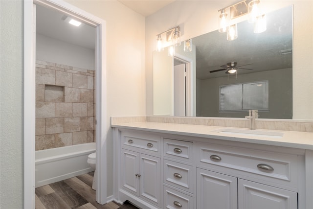 full bathroom featuring toilet, a ceiling fan, washtub / shower combination, vanity, and wood finished floors