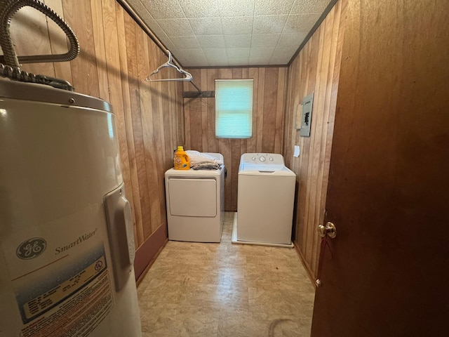 laundry area with wood walls, washing machine and dryer, and light floors