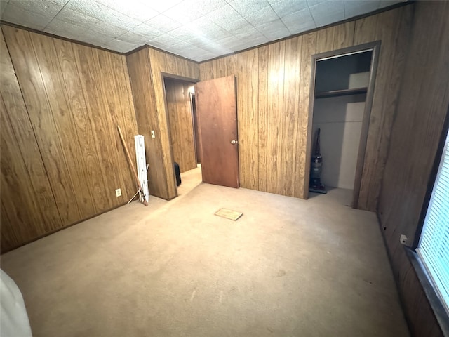 unfurnished bedroom featuring wooden walls, a closet, and light colored carpet