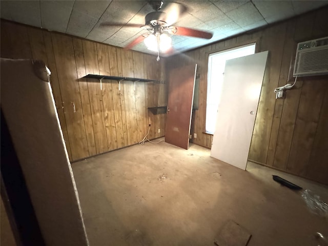 interior space with a ceiling fan, an AC wall unit, and wooden walls