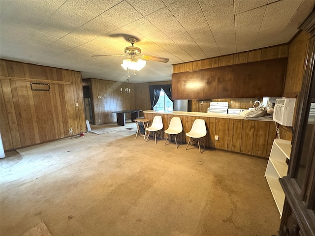 kitchen with a peninsula, brown cabinetry, carpet floors, and light countertops