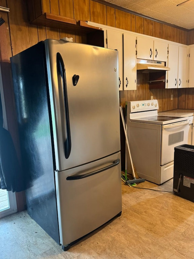 kitchen featuring white cabinets, light floors, freestanding refrigerator, under cabinet range hood, and white range with electric cooktop