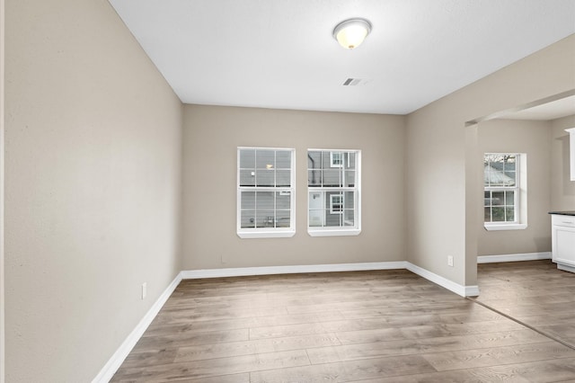 unfurnished room with wood finished floors, visible vents, and baseboards