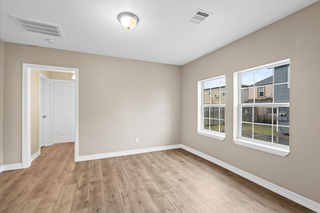 unfurnished room with light wood-style flooring, visible vents, and baseboards