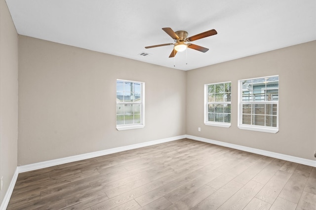 empty room with baseboards, wood finished floors, visible vents, and a ceiling fan