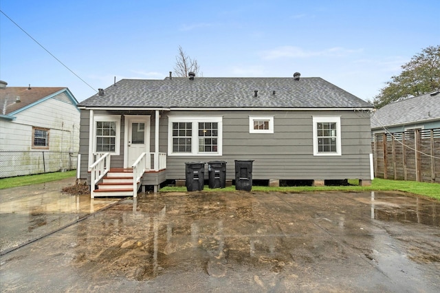 rear view of house featuring a patio area, a shingled roof, and fence