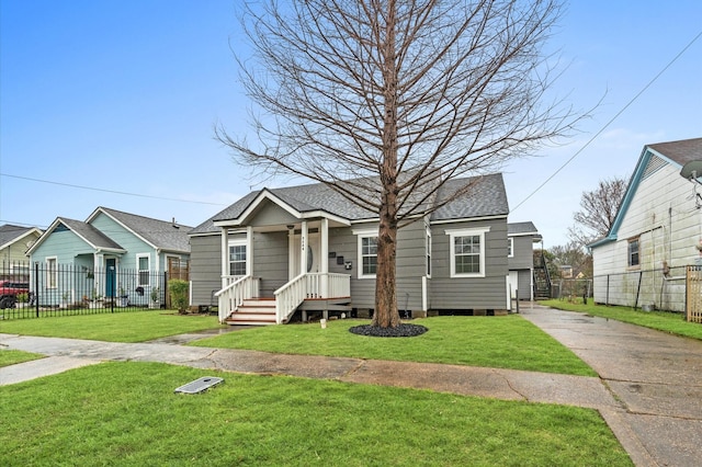 bungalow-style home with roof with shingles, a front yard, and fence