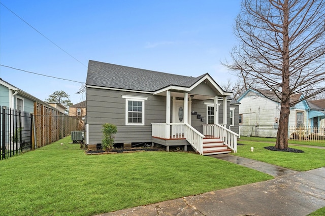 view of front facade featuring a front lawn, roof with shingles, cooling unit, and a fenced backyard