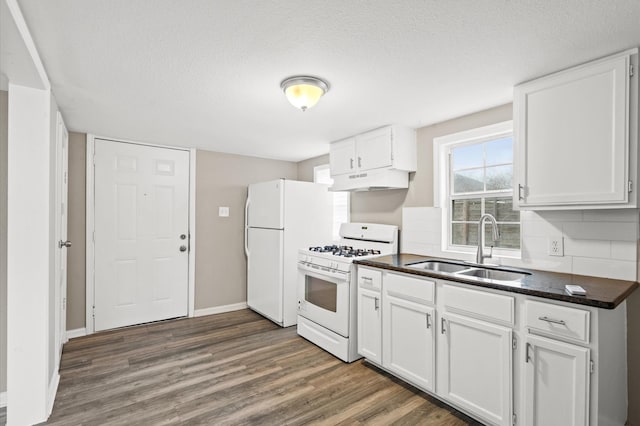 kitchen featuring white appliances, a sink, white cabinetry, dark wood-style floors, and dark countertops