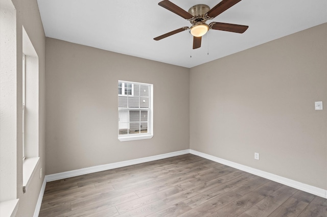 empty room with ceiling fan, wood finished floors, and baseboards