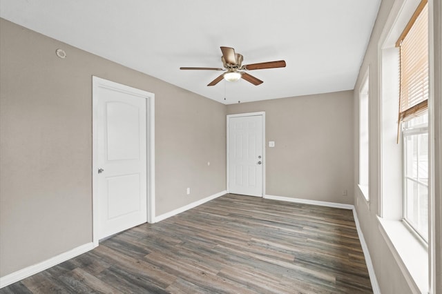 unfurnished room featuring dark wood finished floors, a ceiling fan, and baseboards