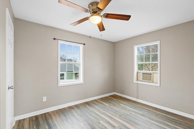 unfurnished room featuring cooling unit, plenty of natural light, wood finished floors, and baseboards