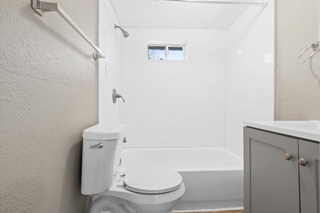 bathroom with toilet, a textured wall, shower / tub combination, and vanity