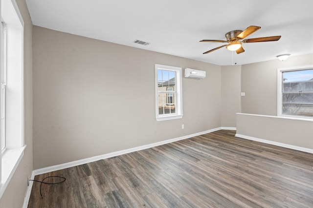 unfurnished room with dark wood finished floors, visible vents, a ceiling fan, an AC wall unit, and baseboards