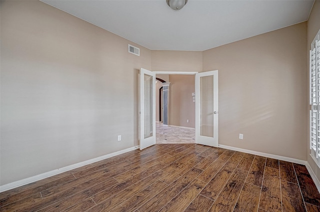 unfurnished room featuring french doors, visible vents, dark wood finished floors, and baseboards