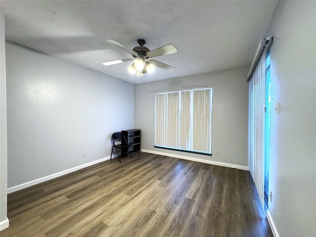 unfurnished bedroom featuring a ceiling fan, a textured ceiling, baseboards, and dark wood-style flooring