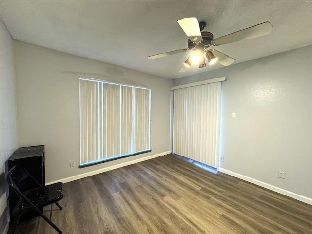 empty room with dark wood-style floors, ceiling fan, and baseboards