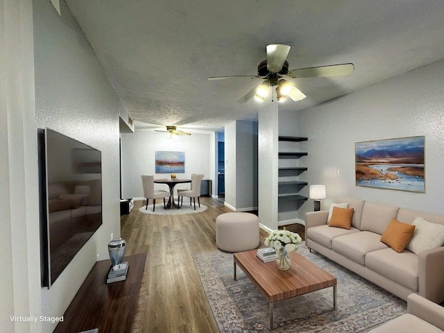 living room featuring ceiling fan, a textured ceiling, wood finished floors, and baseboards