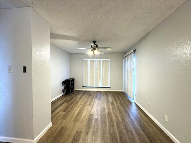 spare room with dark wood-style floors, a textured ceiling, baseboards, and a ceiling fan