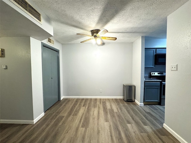 spare room featuring ceiling fan, visible vents, dark wood finished floors, and baseboards