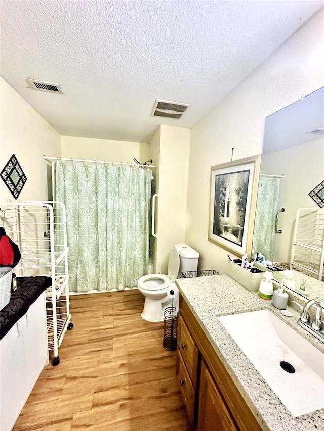 full bath with a textured ceiling, visible vents, wood finished floors, and vanity