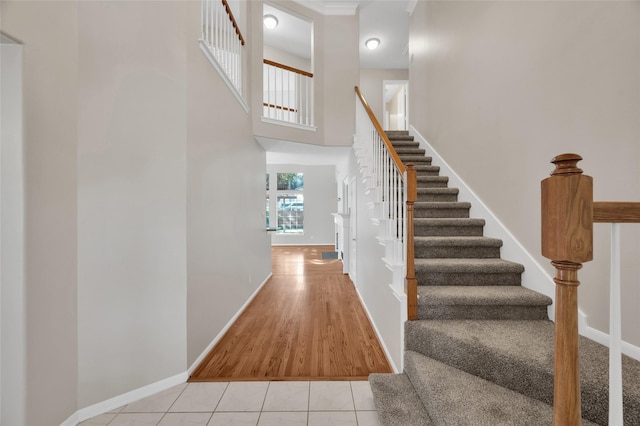 stairs with tile patterned flooring, a towering ceiling, and baseboards