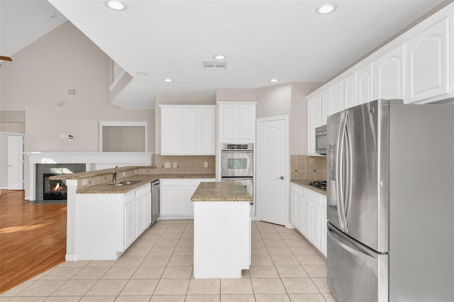 kitchen with appliances with stainless steel finishes, white cabinetry, and a kitchen island