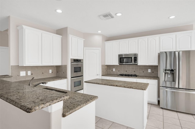 kitchen with stainless steel appliances, visible vents, white cabinetry, a sink, and a peninsula