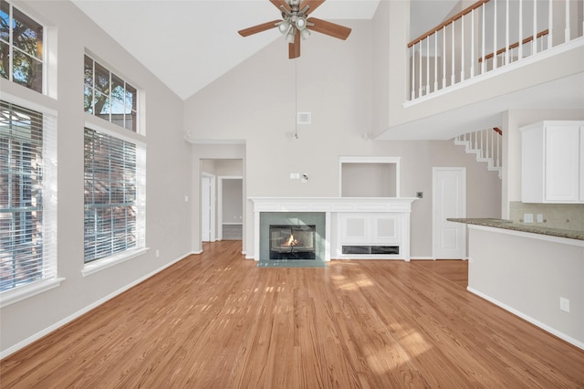 unfurnished living room with light wood-style floors, a glass covered fireplace, and baseboards