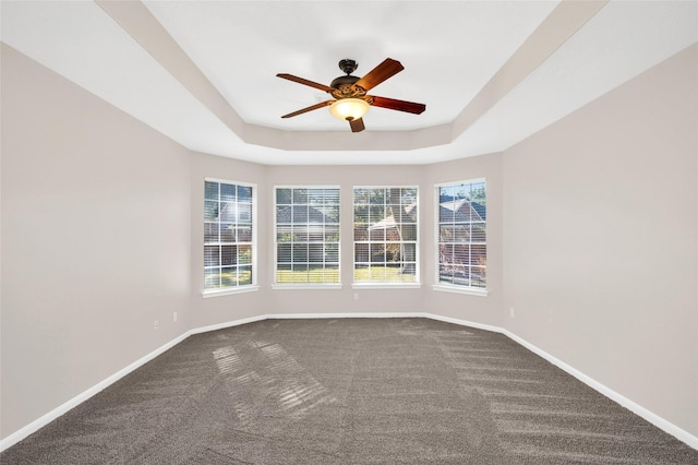 spare room featuring carpet flooring, a raised ceiling, a ceiling fan, and baseboards