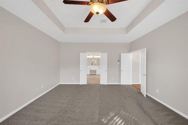 unfurnished bedroom featuring carpet floors, a raised ceiling, visible vents, and baseboards