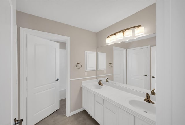 bathroom featuring tile patterned flooring, a sink, baseboards, and double vanity