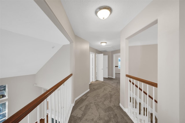 hallway featuring carpet, baseboards, and an upstairs landing