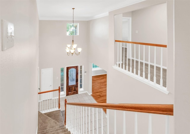 foyer featuring stairs, a high ceiling, a chandelier, and crown molding